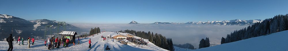 Panoramabild mit Blick von der Gipfelstation der Weltcup-Express-Sesselbahn zur Weltcup-Hütte, im Hintergrund mittig der Grünten
