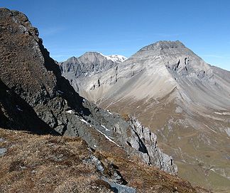 Piz Dolf, rechts, vom Ostende des Fil de Cassons über das Bargistal hinweg gesehen. Der Gipfel ist ganz rechts. Gut sichtbar die Überschiebungslinie; dies auch im Vordergrund; grünlicher Verrucano auf hellem Kalkstein.
