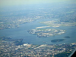 Rikers Island aus der Luft gesehen. Im Hintergrund der Flughafen New York-LaGuardia.